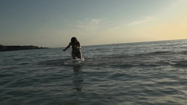 Young girl splashes the water in the ocean