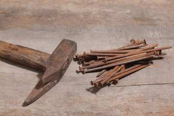 old and rusty claw hammer and nails on a wooden workbench