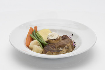 Baked beef marrow with vegetables, decorated with purple leafs, placed on white plate, light background, isolated