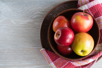 Top view of fresh and organic apples in clay, brown plate on white table