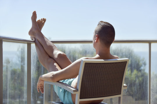 Young Man Sun Tanning In A Chair