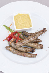 Homemade sausages, served with mustard and decorated with herbs, isolated on light background, white plate
