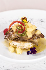 Luxurious dish with duck liver, pineapple and mango pieces, sweet sauce, placed on toasted bread, decorated with eatable flowers and red and green leafs, placed on white plate, light background, isola
