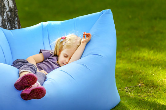 Young Cute Blond Girl Sleeping On An Inflatable Bed Outdoors