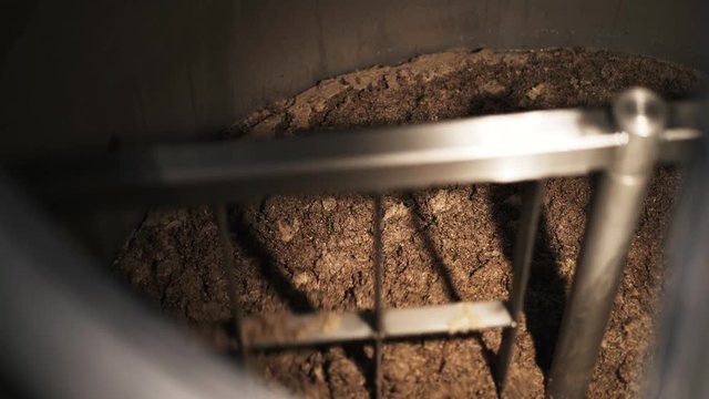 Top view of malt being stirred in a custom beer brewery cask. Handheld real time medium shot