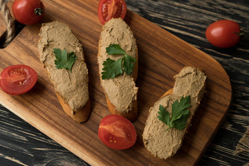 Liver pate on the bread on wooden tray.