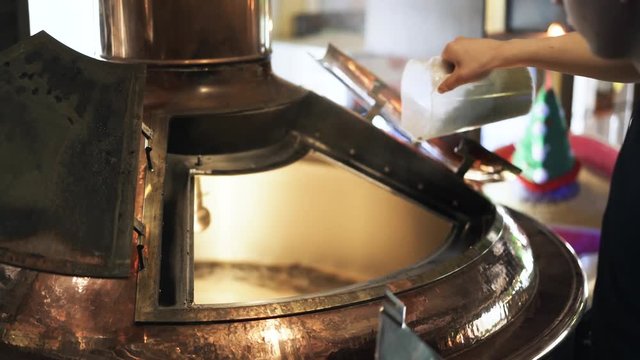 Close up of a young brewery worker s hands opening a lid and adding some malt. Handheld real time close up shot