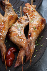 Close-up of skewers with grilled chicken wings, vertical shot, selective focus