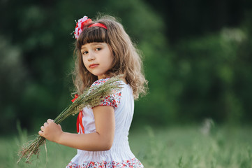 Little girl walks in the forest and collects field plants.