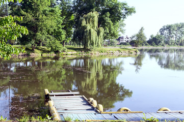 Old pier. Lake, trees, blue sky at dawn.