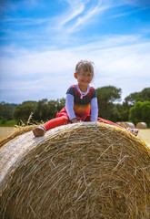 Naklejka na ściany i meble Girl playing over the hay bale outdoor