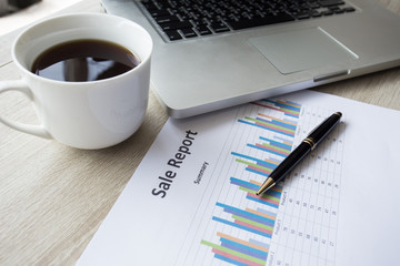 background business stuff, laptop, coffee, pen, graph ,on wooden desk