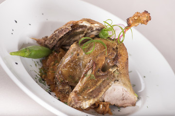 Traditional dish with baked drumstick duck and sour cabbage, decorated with herbs, placed on white plate, light background, isolated