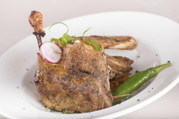 Traditional dish with baked drumstick duck and sour cabbage, decorated with herbs, placed on white plate, light background, isolated