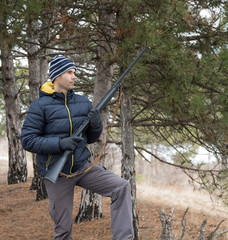 caucasian man in winter forest hunting with a shotgun