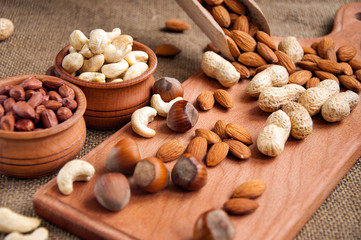 Almonds, cashew and hazelnuts in wooden bowls on wooden and burlap, sack background