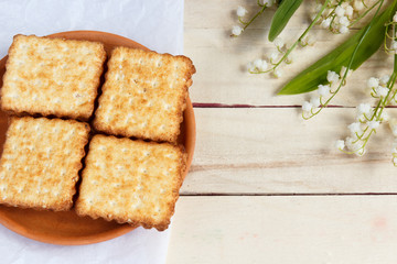 The crackers on the plate. Bouquet of lilies of the valley.