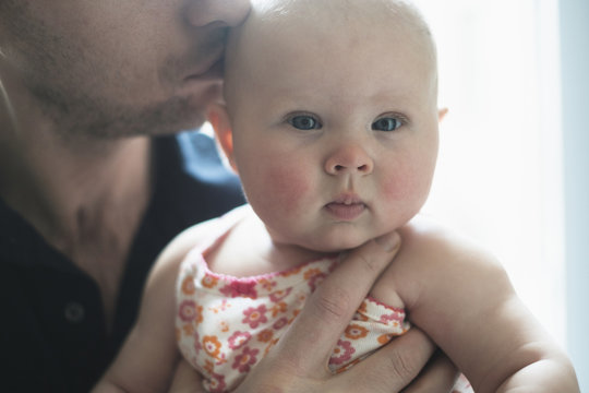 Father kissing daughter's (2-5 months) head