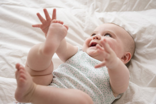 Baby girl lying down with arms and legs up