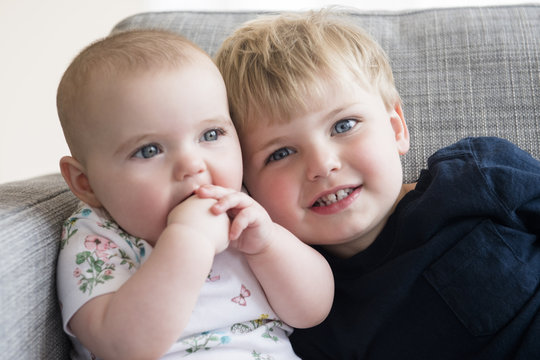 Brother with his baby sister sitting on sofa