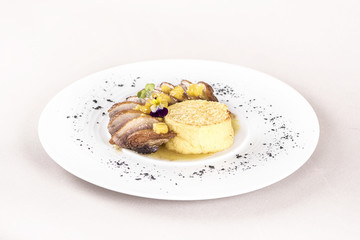 Luxurious dish with slices of duck breast, pineapple pieces, sweet sauce, with potato puree and parmesan, decorated with eatable flowers and red and green leafs, placed on white plate, light backgroun