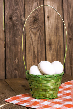 White eggs in the green basket on tablecloth