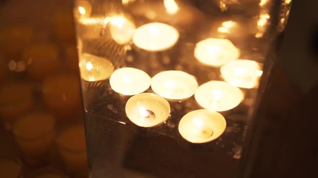 Close up of several floating candles in a glass of water. Beautiful candle light. Atmosphere of romance and love. Handheld real time close up shot