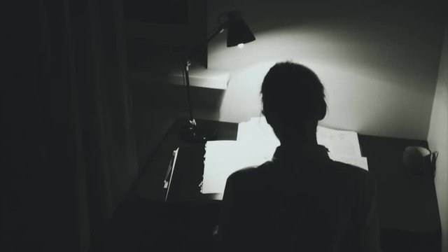 Young woman works in the dark room. Horror atmosphere with camera sneak up.