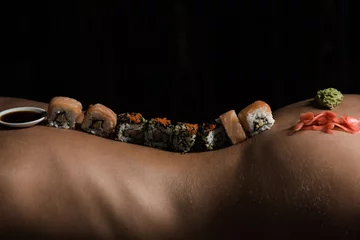 Foto op Plexiglas japanese sushi on sexy female naked body on black background © Volodymyr