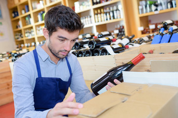 cheerful young man seller wearing uniform in wine house