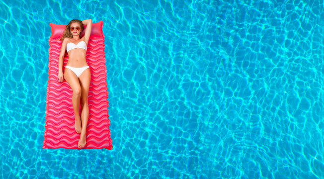Woman in bikini on the inflatable mattress in the swimming pool.