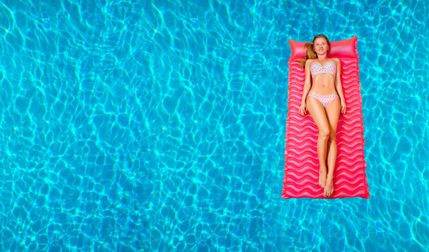 Woman in bikini on the inflatable mattress in the swimming pool.