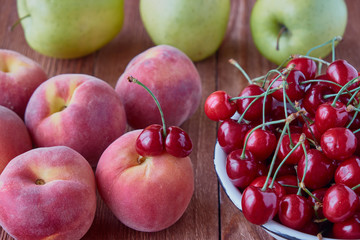 Fresh fruits. Delicious, sweet apples, peaches, cherries on a wooden background.