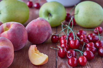 Naklejka na ściany i meble Fresh fruits. Delicious, sweet apples, peaches, cherries on a wooden background.