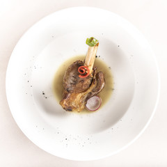 Roasted turkey leg, served with white sauce, decorated with herbs, placed on white plate, light background, isolated