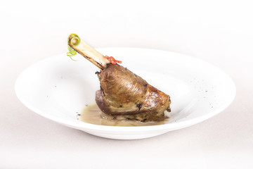 Roasted turkey leg, served with white sauce, decorated with herbs, placed on white plate, light background, isolated