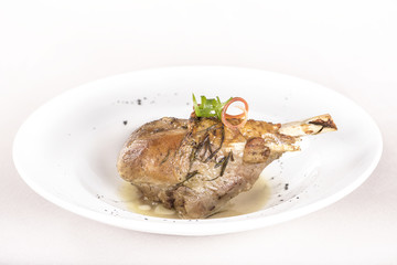 Roasted turkey leg, served with white sauce, decorated with herbs, placed on white plate, light background, isolated