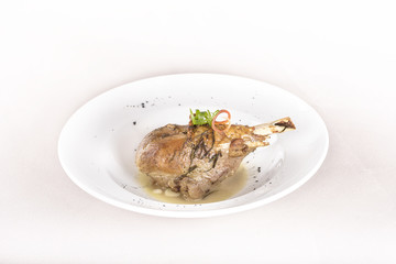 Roasted turkey leg, served with white sauce, decorated with herbs, placed on white plate, light background, isolated