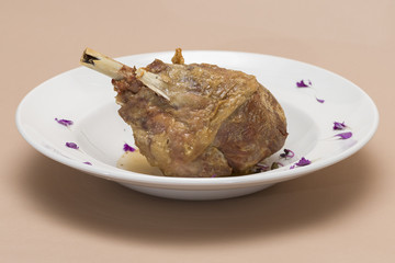 Roasted turkey leg, served with white sauce, decorated with herbs, placed on white plate, light background, isolated