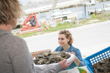 female worker delivering oysters at a fish market
