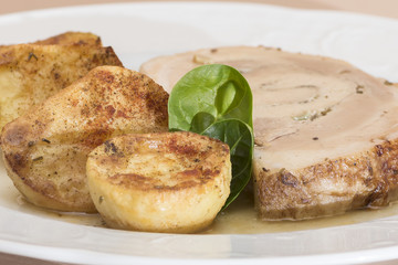 Slice roasted pork, served with potatoes and decorated with herbs, placed on white plate, light background, isolated