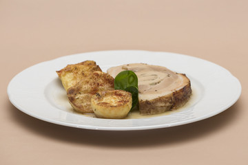 Slice roasted pork, served with potatoes and decorated with herbs, placed on white plate, light background, isolated