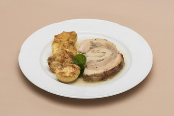 Slice roasted pork, served with potatoes and decorated with herbs, placed on white plate, light background, isolated