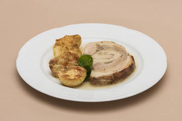 Slice roasted pork, served with potatoes and decorated with herbs, placed on white plate, light background, isolated