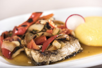 Brine fish plate with vegetables, chili and polenta, placed on white plate, light background, isolated