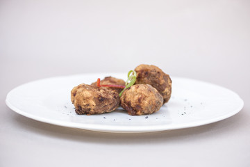 Fried pane sweetbreads, decorated with herbs, isolated on light background, white plate