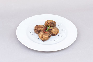 Fried pane sweetbreads, decorated with herbs, isolated on light background, white plate