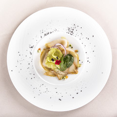 Fresh appetizer with smoked white fish, rucola, baby spinach and green salad, with red eatable flowers, placed on white plate, light background, isolated