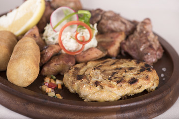 Traditional Romanian food plateau, with sausages, grilled meat, sweetbreads, potatoes, pickles, mustard, polenta, mushrooms, mici and vegetable salad, decorated with herbs, isolated on light backgroun