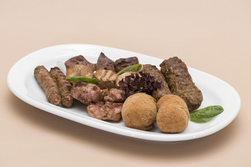 Traditional Romanian food plateau, with sausages, grilled meat, sweetbreads, potatoes, pickles, mustard, polenta, mushrooms, mici and vegetable salad, decorated with herbs, isolated on light backgroun